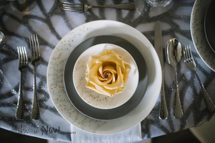 silver and gold place setting with a rose