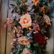 Fall display of blooms with accent of pinecones creating a beautiful hanging impressive display for family gatherings on holidays of oranges, red, and pinecones designed by durham florist poppy belle floral design