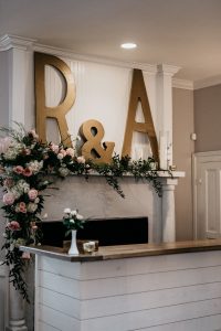initial signs over fireplace and bar with wow floral design by wedding florist in durham nc