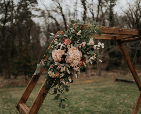 Ceremony flowers of blushes and greenery with geometric arch design by durham florist poppy belle floral design
