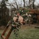 Ceremony flowers of blushes and greenery with geometric arch