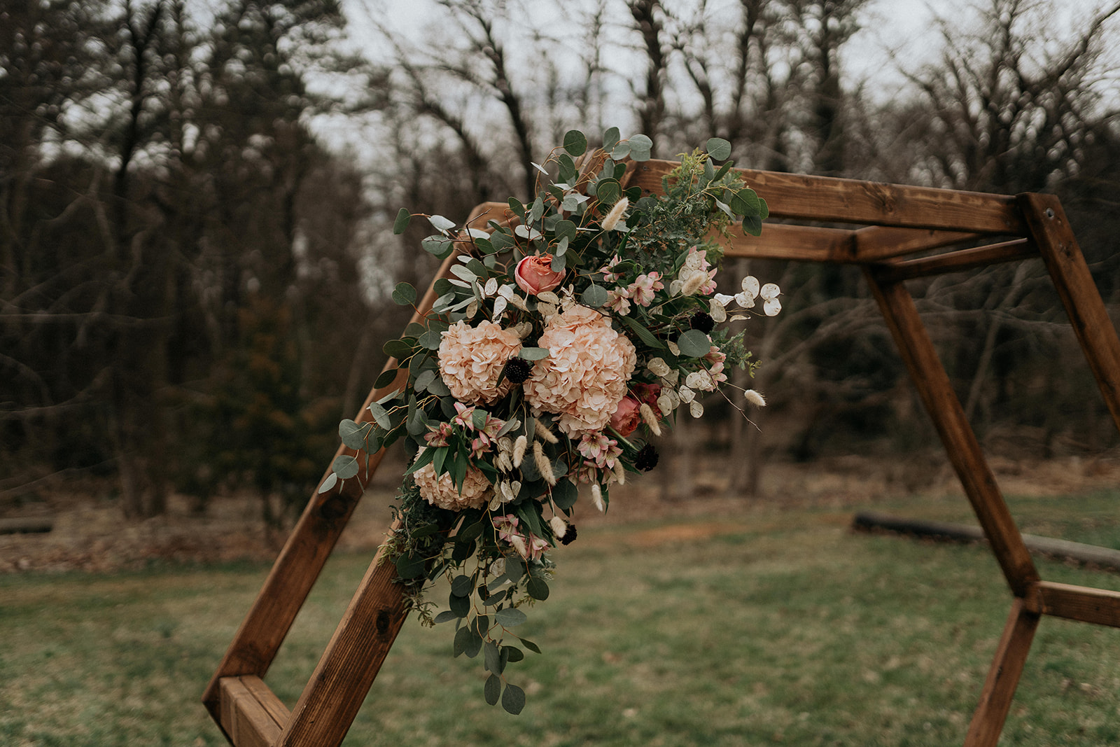 Ceremony flowers of blushes and greenery with geometric arch