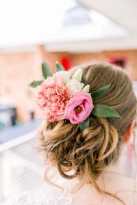 Brides hair accented with blooms in shades of pink designed by durham florist poppy belle floral design