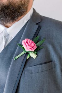 Groom in grey suit close up of pink rose boutonniere by durham florist poppy belle floral design