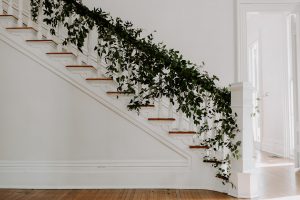 Greenery cascading down hand rail of staircase designed by durham florist poppy belle floral design