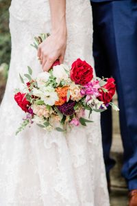 Red, coral, orange and white blooms with greenery bridal bouquet designed by durham florist poppy belle floral design