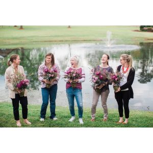 Five women stand in a line holding their floral design created at a floral design workshop taught by durham florist poppy belle floral design
