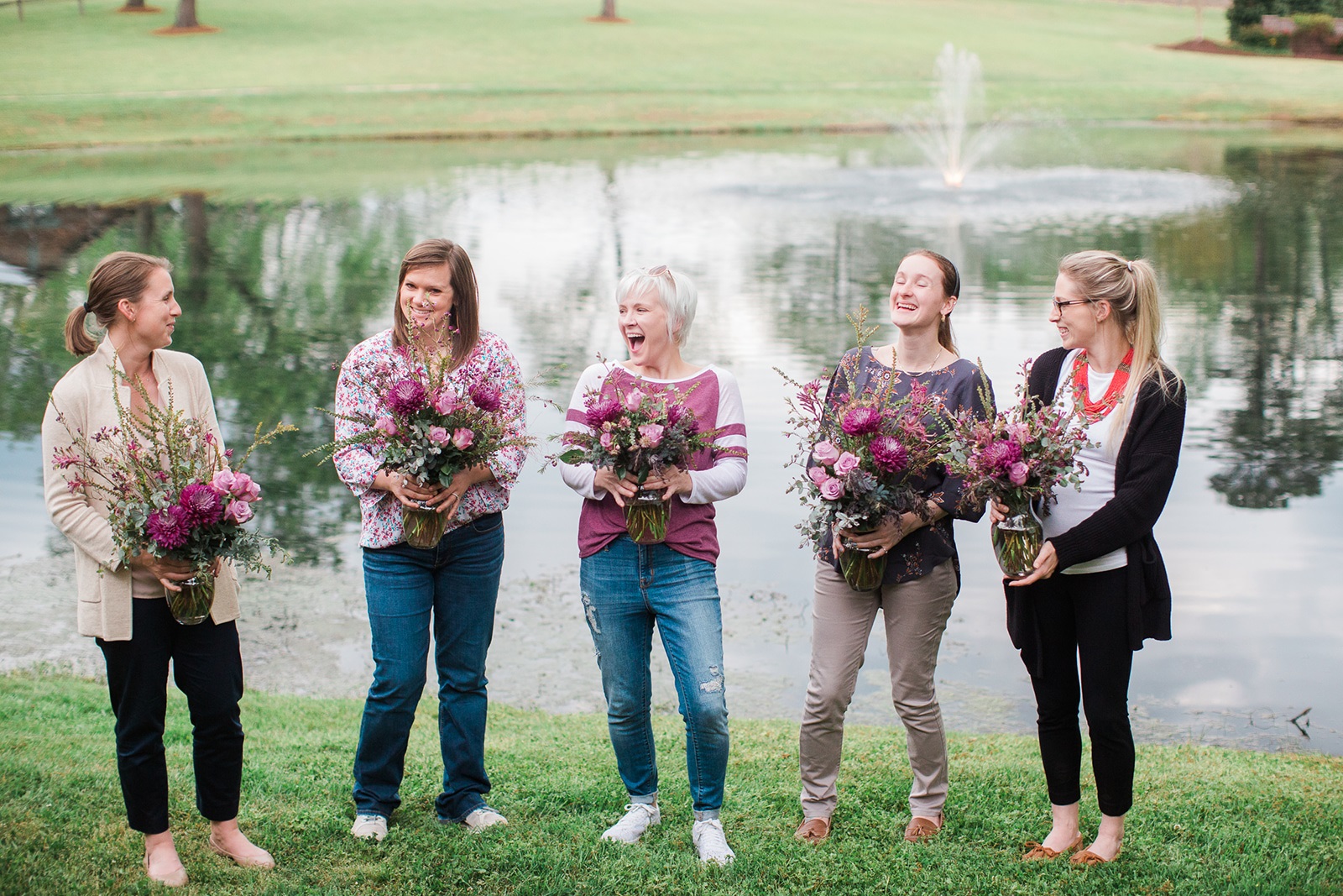 Five women stand in a line holding their floral design created at a floral design workshop taught by durham florist poppy belle floral design